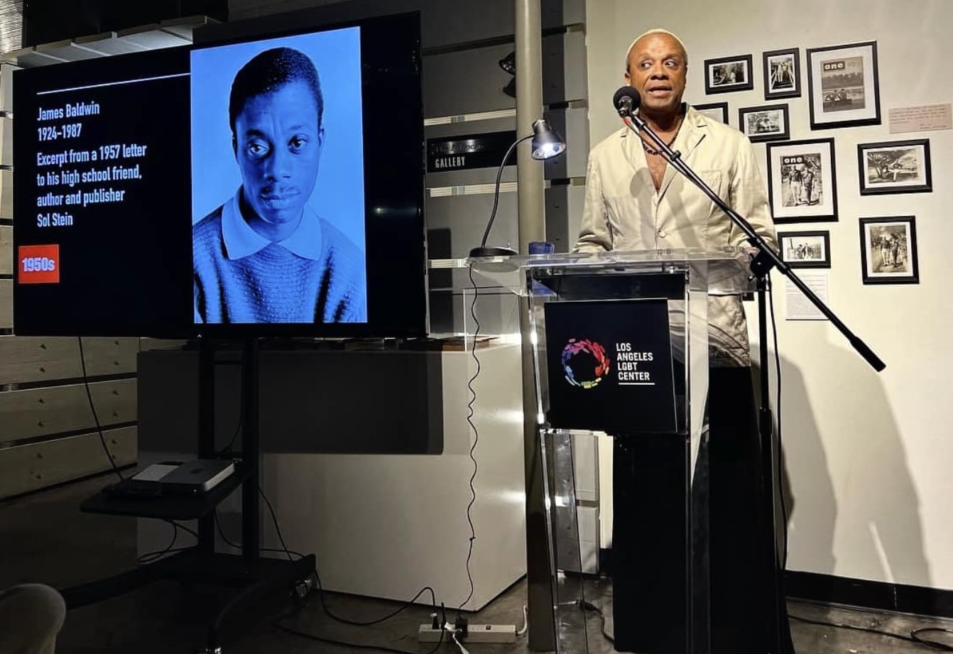 An image of Paul Outlaw at a Podium next to a presentation on James Baldwin.